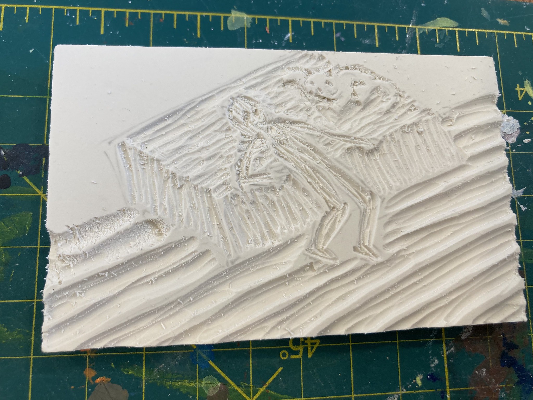 Linocut block with engraving of person hanging off of bed